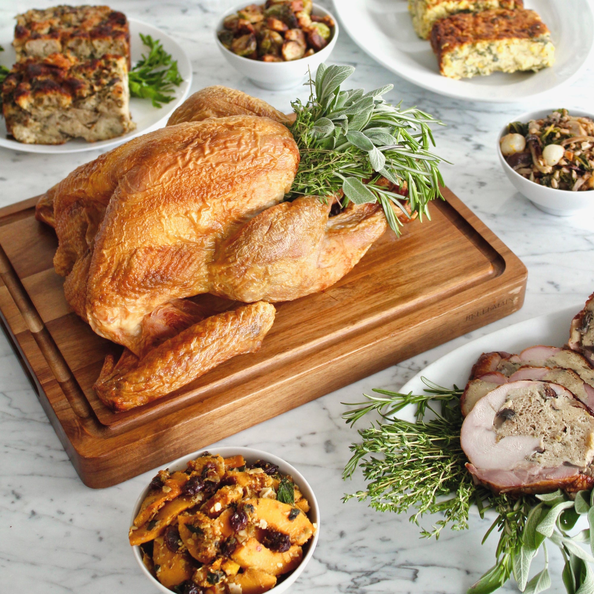 A thanksgiving turkey on a carving board surrounded by sides.