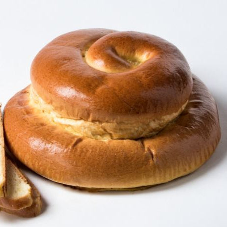 A glossy, golden-brown twisted roll or pretzel-like bread with several slices cut and placed beside it on a clean white background.